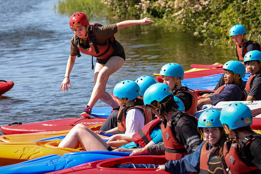 A girl running across a line of kayaks in the water